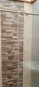 a glass shower in a bathroom with a stone wall at Villa chava in Ibagué