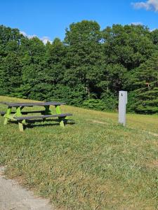 a picnic table sitting in the grass next to a field at Hocking Hills Store Campsite #4 in Logan +2 photos
