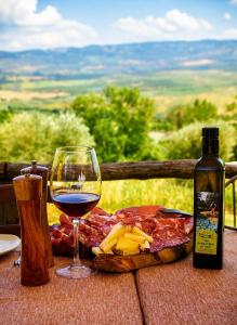 a bottle of wine and a glass of meat and cheese at Il Cerchio delle Streghe Country House al Podere Casella in Castiglione dʼOrcia +11 photos