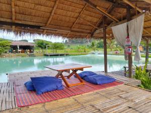 a picnic table with two blue pillows next to a pool at ecolodge khamu homestay guesthouse in Ban Pak Ing