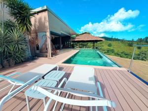 a deck with chairs and a swimming pool at Villa Maeva Tahiti in Vaihi