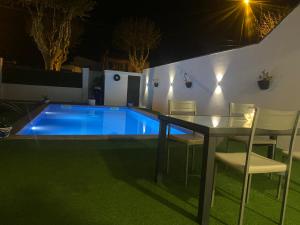a table and chairs next to a swimming pool at night at Casa en empuriabrava in Empuriabrava