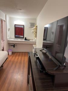 a room with a bed and a desk with a flat screen tv at Coastline Motel Kamloops in Kamloops
