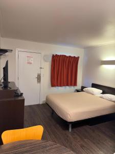 a room with a bed and a television and a window at Coastline Motel Kamloops in Kamloops