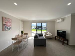 a living room with a couch and a table and a television at Sweet Serendipity in Tauranga