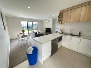 an open kitchen and living room with a blue trash can at Sweet Serendipity in Tauranga