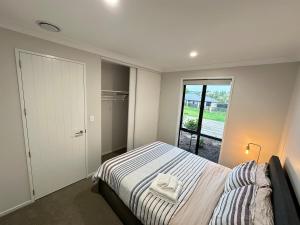 a bedroom with a bed and a large window at Sweet Serendipity in Tauranga