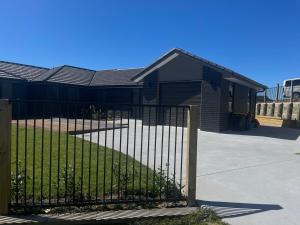 a black fence in front of a house at Sweet Serendipity in Tauranga