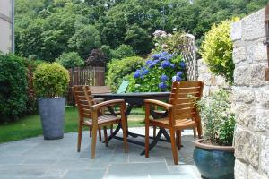 a patio with a table and chairs and flowers at La Sabotiere in Pluméliau