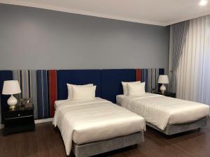 two beds in a hotel room with two lamps at Indigen Boutique Hotel Cao Bang in Cao Bằng