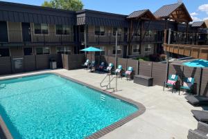 a pool with chairs and umbrellas in front of a building at The Hotel Y, a Dazzler Select by Wyndham in Yakima