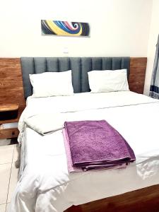 a bed with a purple blanket on top of it at KiGALI CLASSIC LODGE in Kigali +8 photos