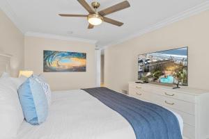 a white bedroom with a bed and a flat screen tv at A217 - Blue Water Escape in Oceanside +55 photos