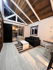 a living room with a black couch and a table at Cabañas Laguna Magica in Valdivia