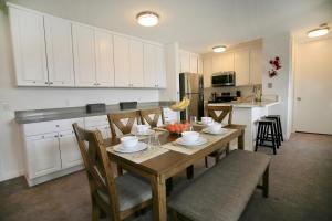a kitchen with a wooden table with chairs and a kitchen with white cabinets at A300 - Pier View Paradise in Oceanside
