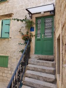 a green door on the side of a building with stairs at Villa Kuljis in Komiža