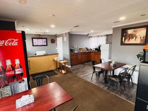a restaurant with two tables and a cocacola refrigerator at Wheel Inn Motel in Assiniboia