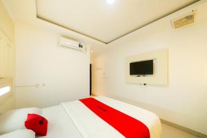 a bedroom with a red and white bed and a tv at JM Tuparev Mitra RedDoorz in Karawang
