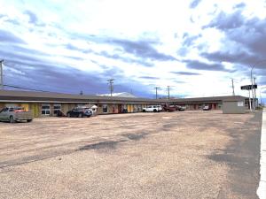 a building with cars parked in a parking lot at Wheel Inn Motel in Assiniboia