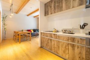 a kitchen with wooden cabinets and a dining table at HOPETREE HAKUBA in Hakuba