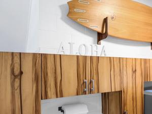 a surfboard on the wall of a bathroom at Coral Wave Cottage in Waialua