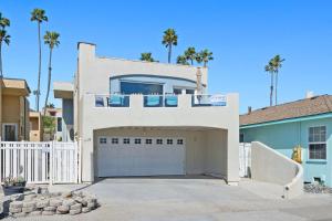 a white house with a garage and palm trees at Sunset On The Strand in Oceanside