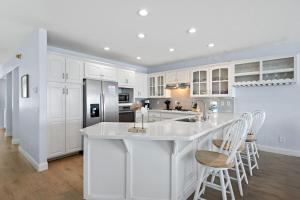a kitchen with white cabinets and a kitchen island with stools at Sunset On The Strand in Oceanside