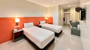 a hotel room with two beds and an orange wall at Travelbee Airport Inn in Mactan