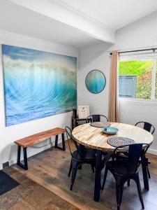 a dining room with a table and chairs and a painting at Coral Wave Cottage in Waialua