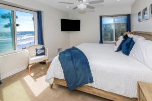 a bedroom with a bed and a tv and windows at D313 - Sea Blue in Oceanside +53 photos