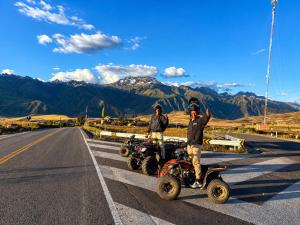 two men standing on four wheelers on a road at Chaska Valle Green in Urubamba