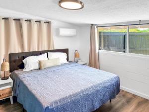 a bedroom with a bed and a large window at Coral Wave Cottage in Waialua