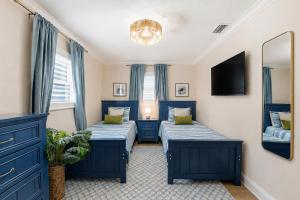 two beds in a room with blue curtains and a mirror at Sunwashed Stone Villa with Heated Pool, Hot Tub & Mini Golf in Bradenton