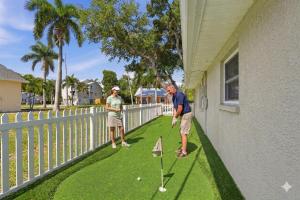 two people playing a game of golf on the porch of a house at Sunwashed Stone Villa with Heated Pool, Hot Tub & Mini Golf in Bradenton +9 photos