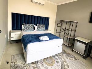 a bedroom with a large bed with a blue headboard at MRF Lodge in Louis Trichardt