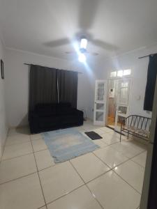 a living room with a black couch on a tiled floor at Casa Prox Centro in Ribeirão Preto