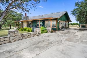 a green house with a stone wall at Nueces River Escape in Uvalde