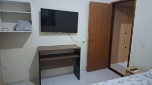 a bedroom with a desk with a television on a wall at Suíte privativa com acesso à rua in Dourados