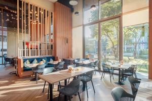 a restaurant with tables and chairs and large windows at Oakwood Suites Bangkok in Bangkok