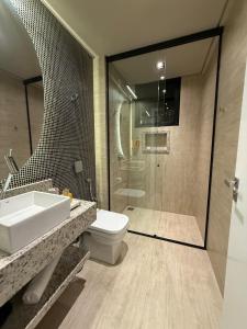a bathroom with a toilet and a sink and a shower at Suite Boutique 101 Cheia de Graca in Divinópolis