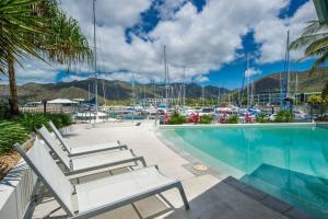 a swimming pool with lounge chairs next to a marina at Blue on Blue Studio Room 1352 in Nelly Bay