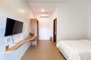 a bedroom with a bed and a tv on a wall at Urbanview Hotel Syariah Nawasena Guest House IKN by RedDoorz in Sepaku