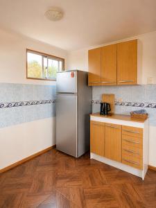 a kitchen with a refrigerator and wooden cabinets at Viento Sur Astro Camping & Cabañas in Los Hornitos