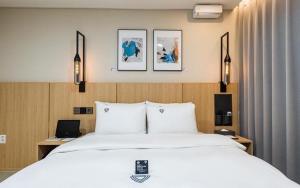 a bedroom with a large white bed and two lights at Daejeon Continew Hotel in Daejeon
