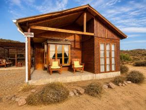 a small log cabin with two chairs and a porch at Viento Sur Astro Camping & Cabañas in Los Hornitos +36 photos