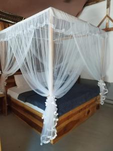 a bed with mosquito netting on it in a room at Surfers Park Arugambay in Arugam Bay