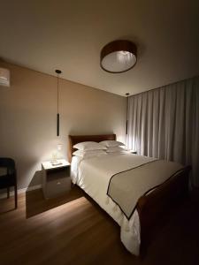 a bedroom with a large bed and a night stand at Suite Boutique 102 Cheia de Graça in Divinópolis