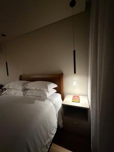 a bedroom with two beds and a table with a book at Suite Boutique 102 Cheia de Graça in Divinópolis