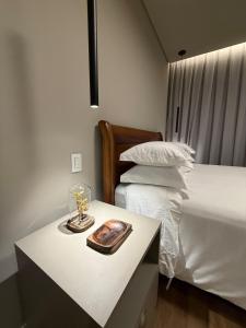 a bedroom with a bed and a table with a candle at Suite Boutique 102 Cheia de Graça in Divinópolis