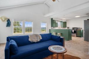 a living room with a blue couch and a kitchen at Nueces River Escape in Uvalde